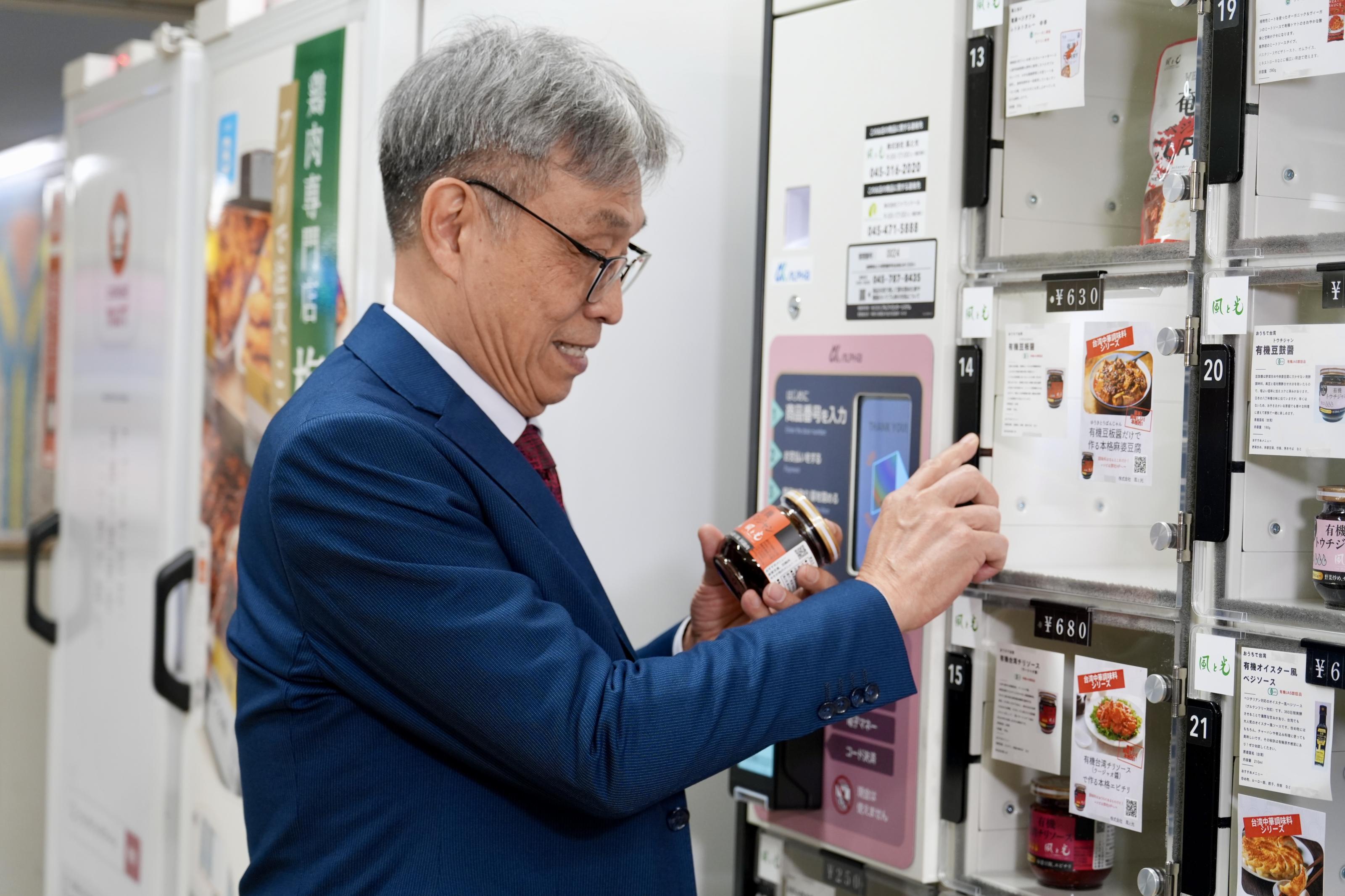 照片3_陳駿季部長體驗橫濱車站內設置的SDGs置物櫃型自動販賣機