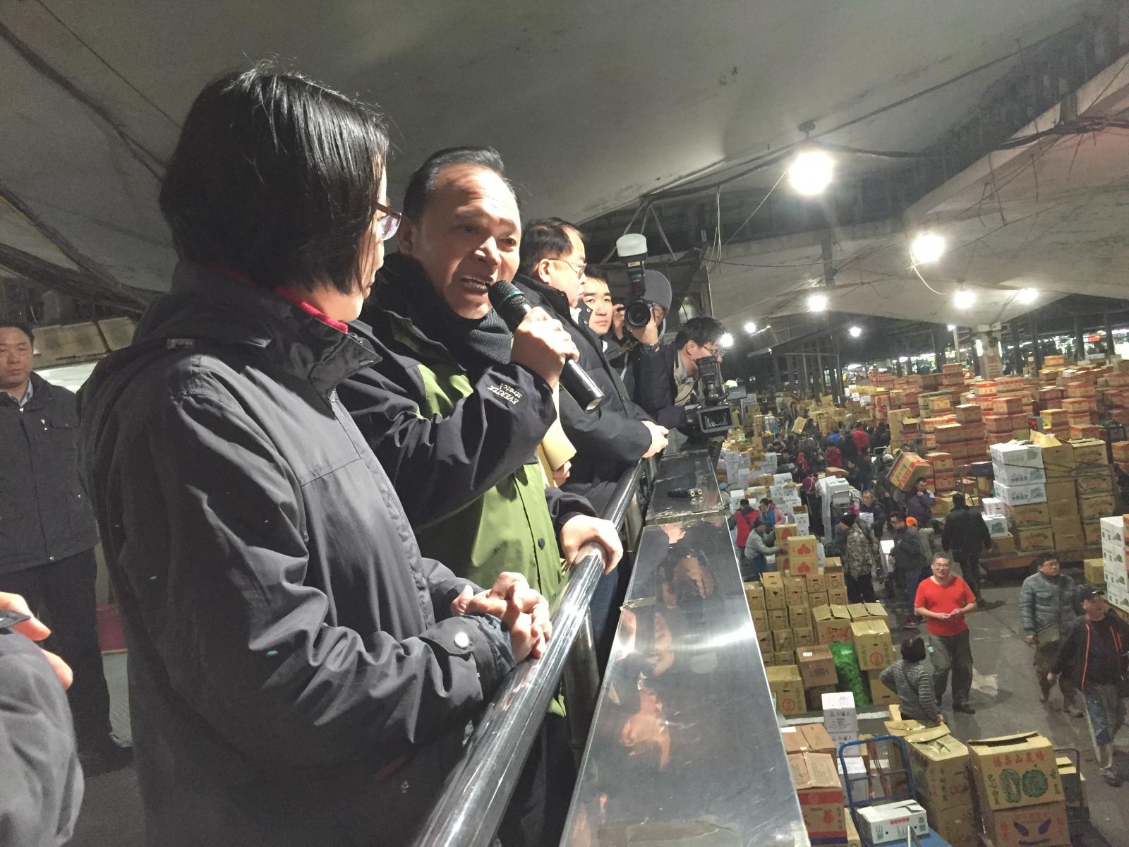 林主委(左二)在蔬果拍賣場指揮臺 向供銷業者問候