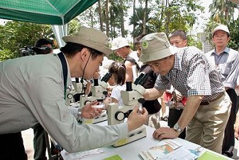 陳主委武雄透過顯微鏡觀察鳥類的特殊羽毛構造。
